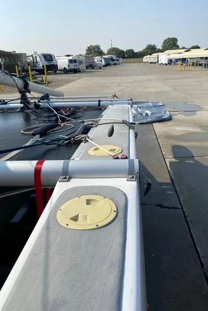 Slide: The Image of 1989 Nacra 5.8 catamaran on a concrete surface, surrounded by parked vehicles. - 18