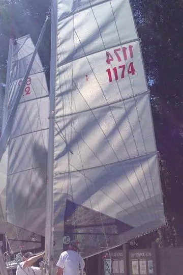 Slide: The Image of Sailboat with Nacra 5.8 sails, 1989 model, docked with people adjusting rigging. - 22