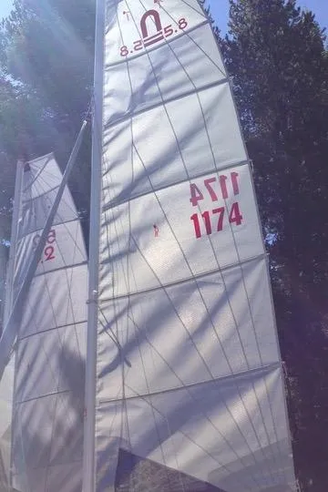 Slide: The Image of Sailboat with Nacra 5.8 sails, model year 1989, against a forest backdrop. - 23