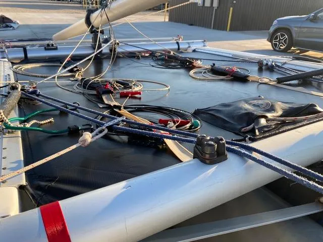 Slide: The Image of 1989 Nacra 5.8 catamaran deck with rigging and ropes in a parking area. - 3