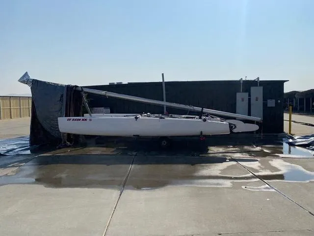 Slide: The Image of 1989 Nacra 5.8 catamaran stored outdoors on a sunny day. - 6