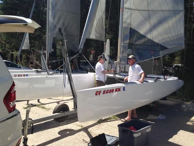 Slide: The Image of Two people preparing a 1989 Nacra 5.8 sailboat on a sunny day. - 8