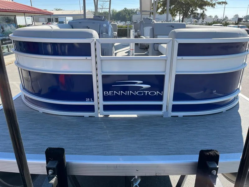 Slide: The Image of 2023 Bennington 25LSRTDSP pontoon boat, blue and white design, displayed outdoors. - 5