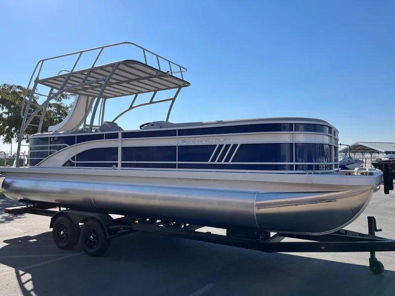 Slide: The Image of 2023 Bennington 25LSRTDSP pontoon boat on trailer, side view under clear sky. - 6