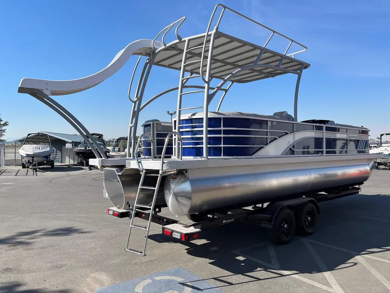 Slide: The Image of 2023 Bennington 25LSRTDSP pontoon boat with slide, parked on trailer in sunny lot. - 8