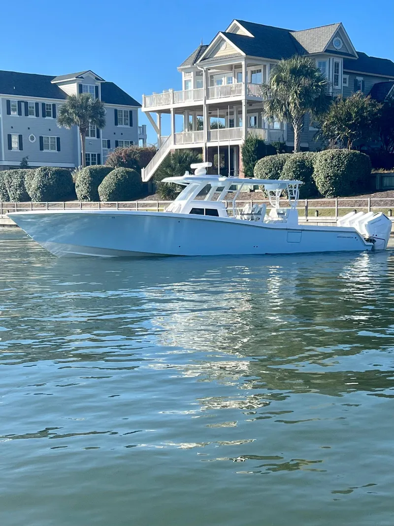Slide: The Image of 2024 Invincible 43 Open Fisherman boat docked near waterfront homes. - 0