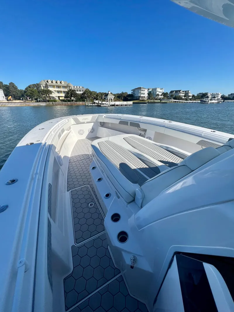 Slide: The Image of 2024 Invincible 43 Open Fisherman boat on calm waters near coastal homes. - 21