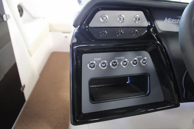 Slide: The Image of 2024 MasterCraft NXT22 boat control panel with switches and storage compartment. - 16