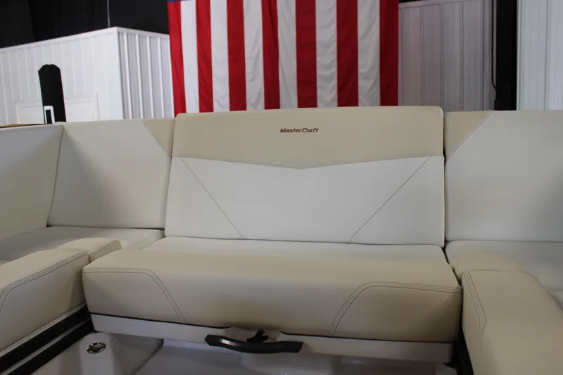 Slide: The Image of 2024 MasterCraft NXT22 boat interior with beige seating and American flag backdrop. - 21