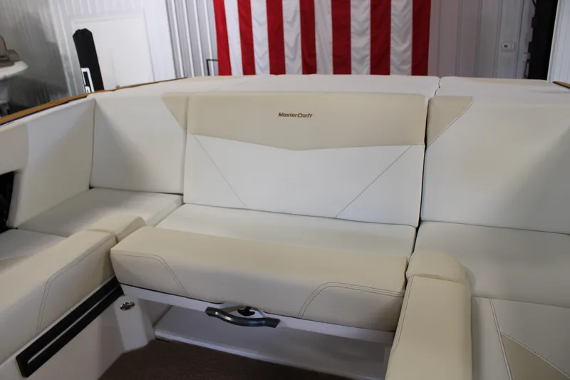 Slide: The Image of 2024 MasterCraft NXT22 boat interior with beige seating and American flag backdrop. - 22