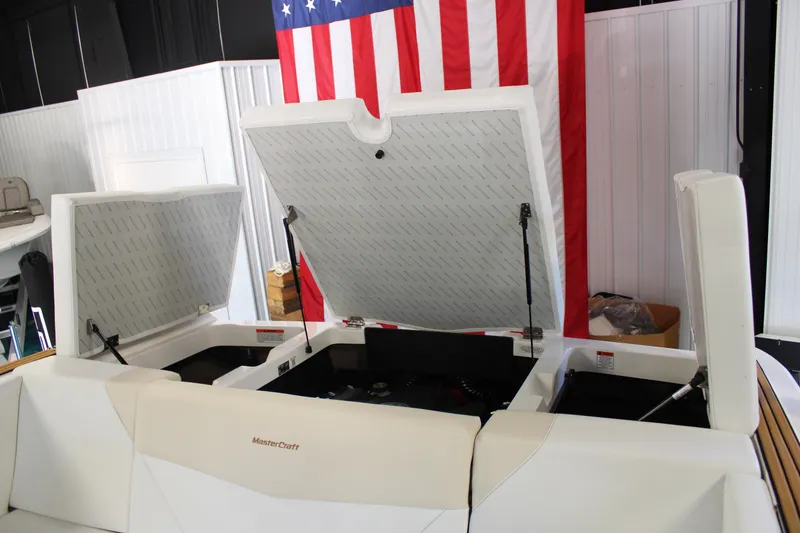 Slide: The Image of 2024 MasterCraft NXT22 boat with open storage compartments, American flag in background. - 31