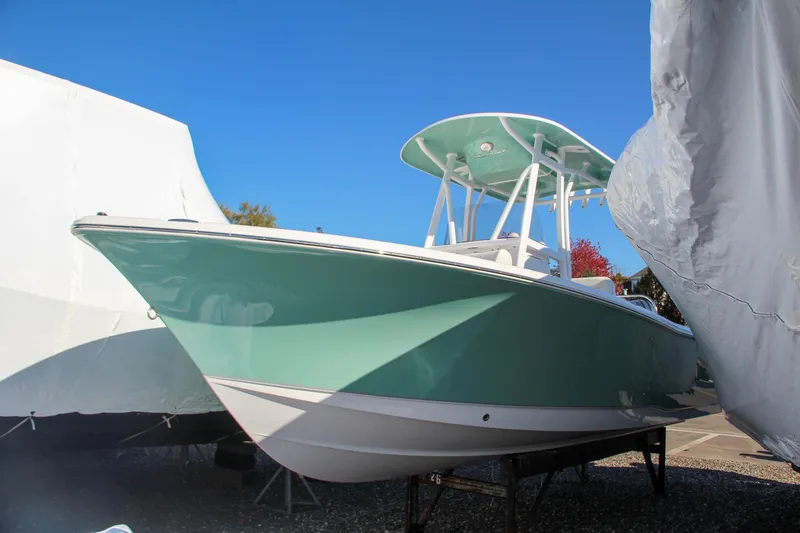 Slide: The Image of 2024 Sea Hunt Ultra 229 boat in storage, teal hull, and T-top. - 11