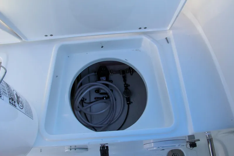 Slide: The Image of Storage compartment of 2024 Sea Hunt Ultra 229 boat with coiled hose. - 20