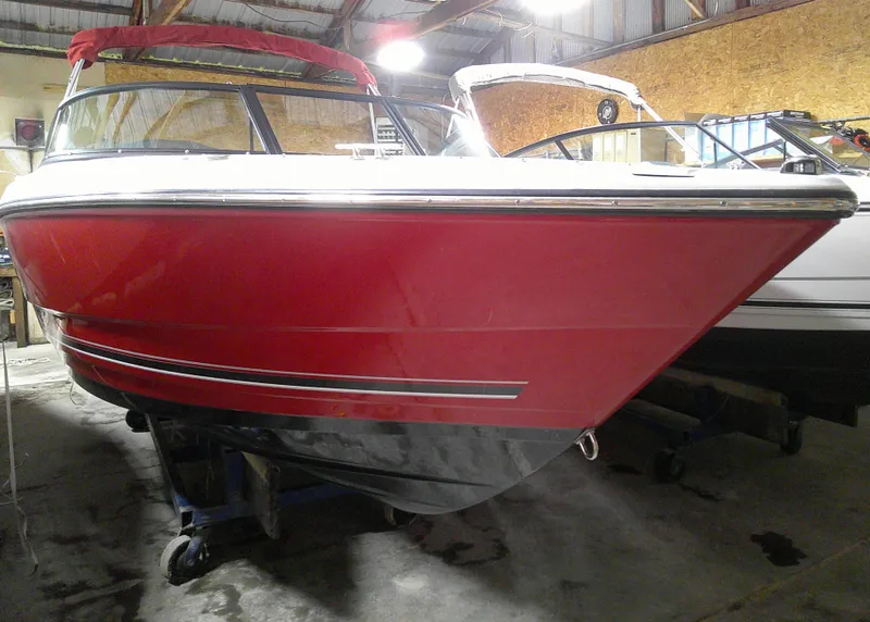 Slide: The Image of 2023 Monterey 224FS boat in red and black, stored indoors. - 0