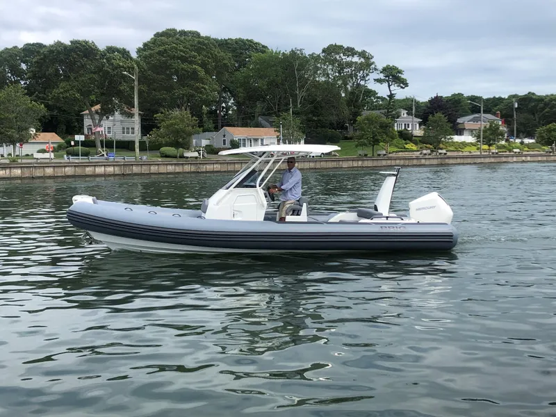 The Image of 2024 Brig Eagle 8 boat cruising on a calm lake near a residential area. - 0