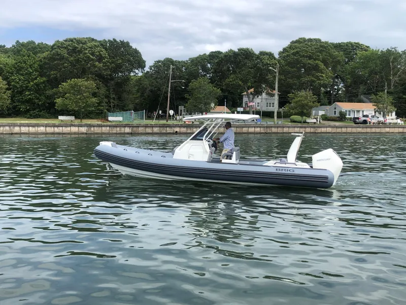 Slide: The Image of 2024 Brig Eagle 8 boat cruising on a calm lake near a residential area. - 13