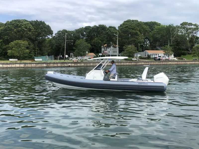 Slide: The Image of 2024 Brig Eagle 8 boat cruising on a calm lake near a wooded shoreline. - 14