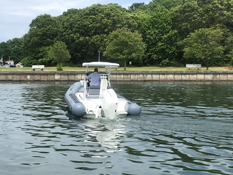 Slide: The Image of 2024 Brig Eagle 8 boat cruising on a calm lake near a wooded shoreline. - 2