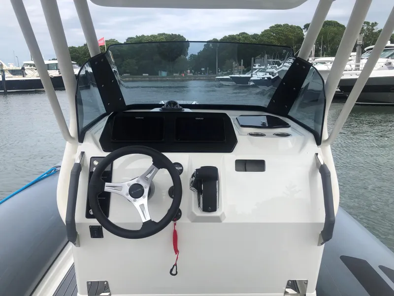 Slide: The Image of 2024 Brig Eagle 8 boat dashboard with steering wheel and controls at marina. - 8