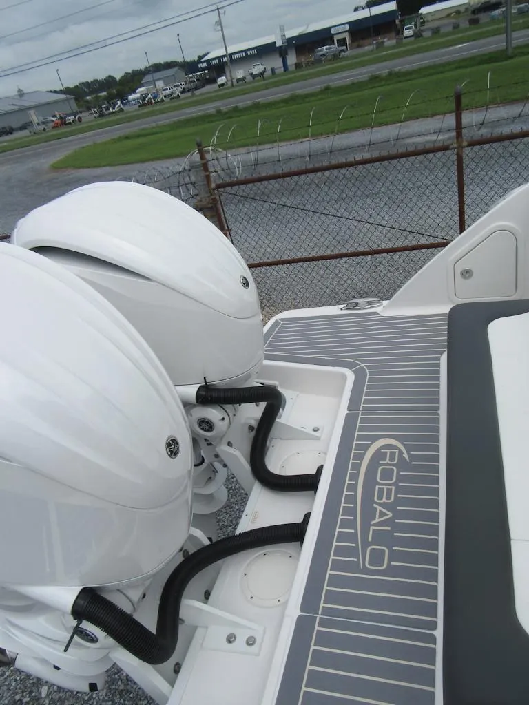 Slide: The Image of 2024 Robalo R317 Dual Console boat with twin engines, docked outdoors. - 26