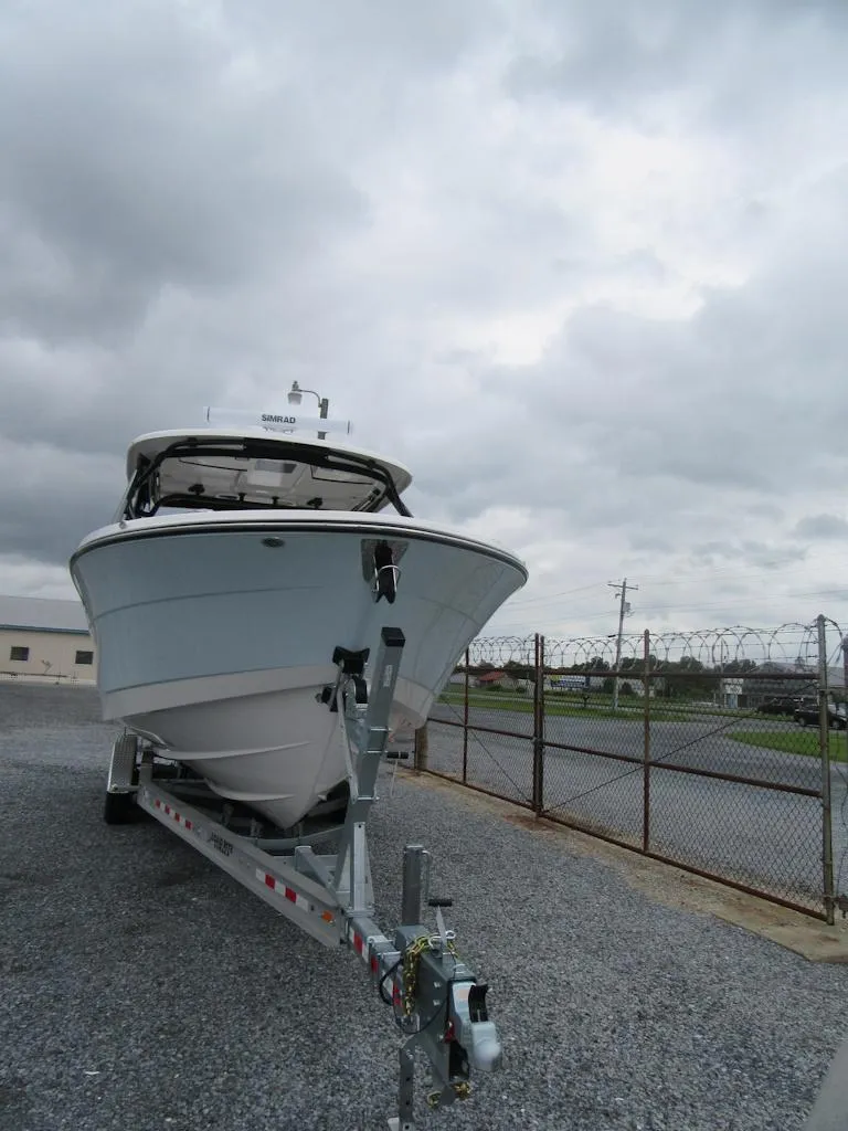 Slide: The Image of 2024 Robalo R317 Dual Console boat on trailer under cloudy sky. - 5