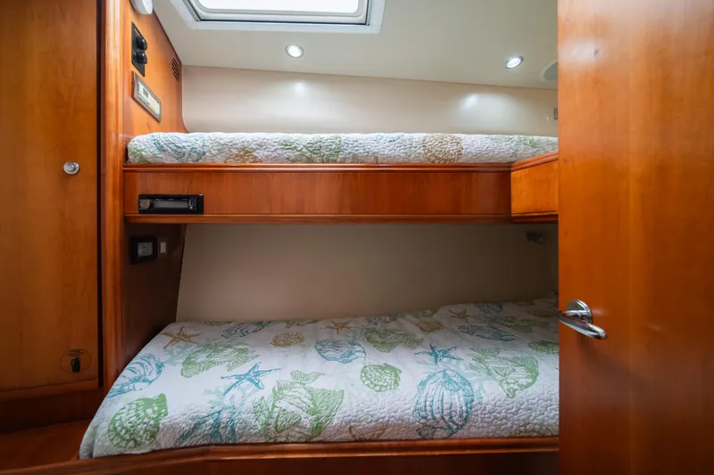 Slide: The Image of Bunk beds in the 2009 Bertram 630 yacht cabin with wooden interior and patterned bedding. - 33
