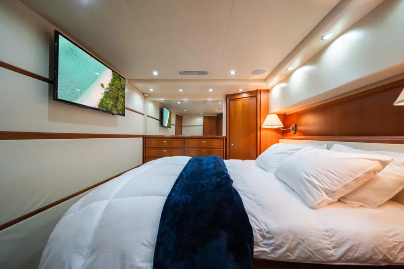 Slide: The Image of Luxurious bedroom interior of 2009 Bertram 630 yacht with TV, wooden cabinets, and cozy bedding. - 34