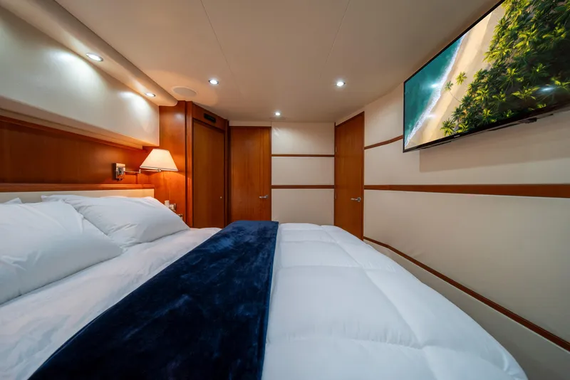 Slide: The Image of Luxurious bedroom interior of 2009 Bertram 630 yacht with cozy bedding and wall-mounted TV. - 36