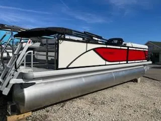 Slide: The Image of 2024 Sweetwater 2286SFL pontoon boat with red and white exterior, docked on gravel. - 2