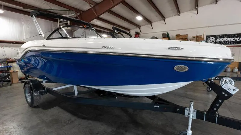 The Image of 2024 Bayliner DX 2000 boat in a showroom, featuring a sleek blue and white design. - 1
