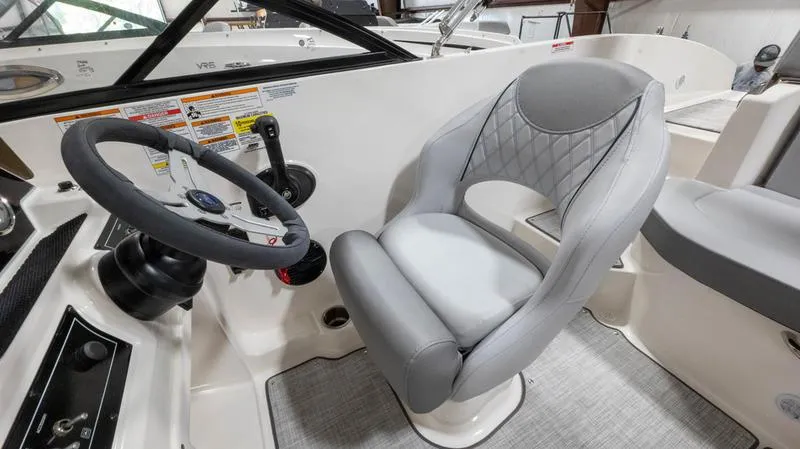 Slide: The Image of 2024 Bayliner DX 2000 boat interior with steering wheel and cushioned seat. - 10