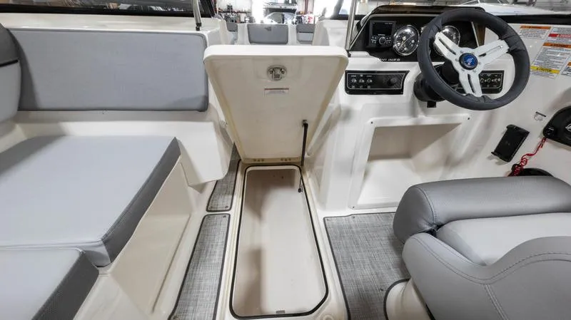 Slide: The Image of 2024 Bayliner DX 2000 boat interior with open storage compartment and steering wheel. - 23