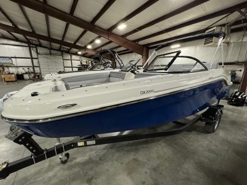 Slide: The Image of 2024 Bayliner DX 2000 boat in a warehouse, featuring a sleek blue and white design. - 8
