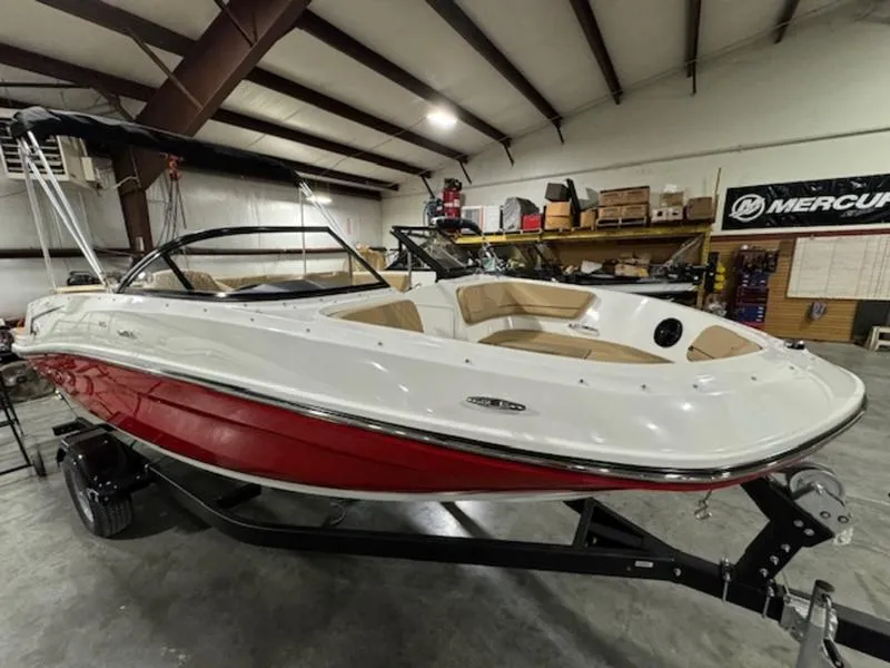 The Image of 2024 Bayliner VR5 Bowrider Outboard in a showroom, red and white hull. - 1