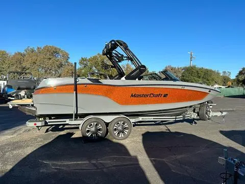 The Image of 2024 MasterCraft XT24 boat on a trailer in a parking lot. - 0