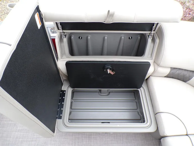 Slide: The Image of Sun Tracker PARTY BARGE® 20 DLX 2024 storage compartment with open seat cushion. - 20