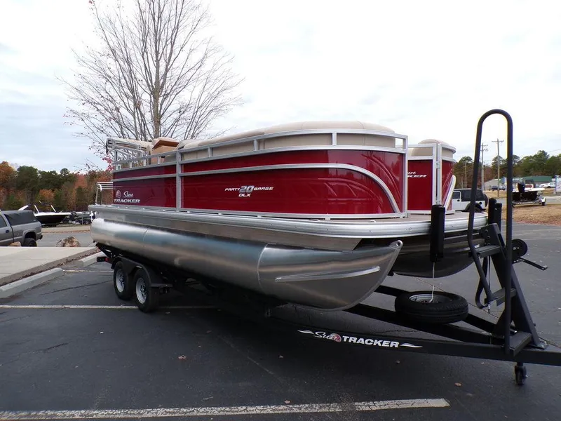 Slide: The Image of 2024 Sun Tracker PARTY BARGE® 20 DLX pontoon boat on a trailer in a parking lot. - 9