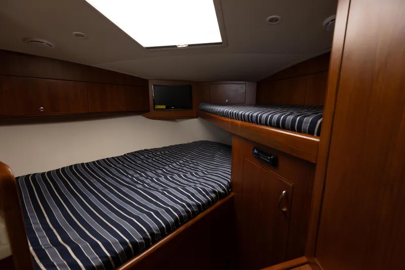 Slide: The Image of 2013 Cabo 36 Express cabin with striped bedding and wooden cabinetry. - 14