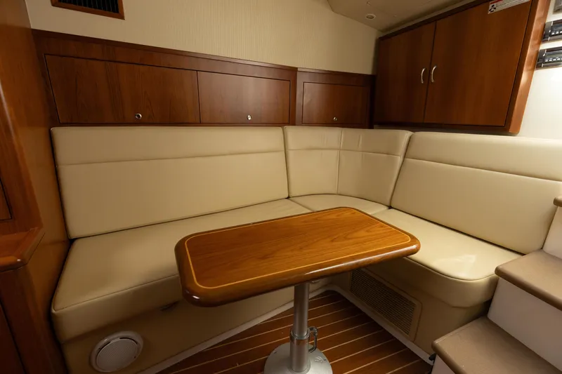 Slide: The Image of 2013 Cabo 36 Express yacht interior with beige leather seating and wooden table. - 15
