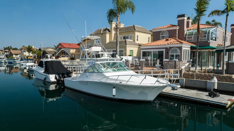 Slide: The Image of 2013 Cabo 36 Express yacht docked in a scenic marina with waterfront homes. - 3