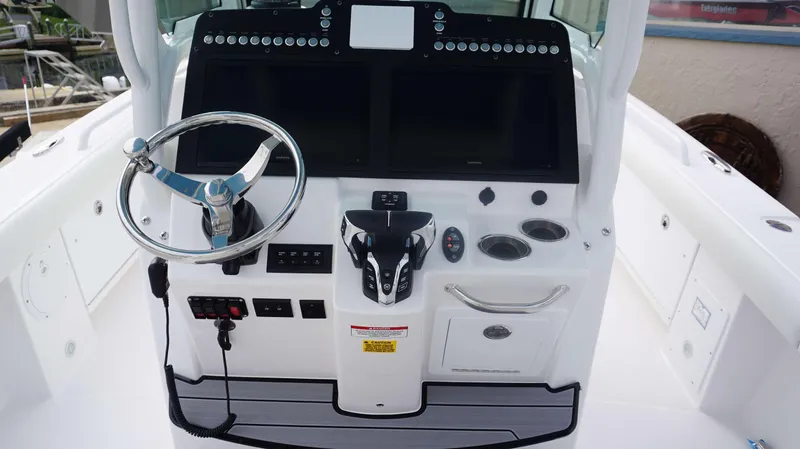 Slide: The Image of 2024 Everglades 273 CC boat helm with steering wheel, dual Garmin displays, and control panel. - 3