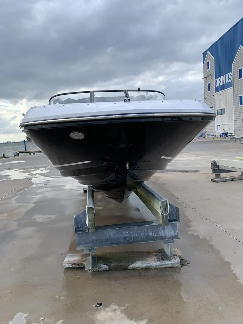 Slide: The Image of 2020 Bayliner VR6 Bowrider I/O on a boat lift, dockside under cloudy skies. - 3