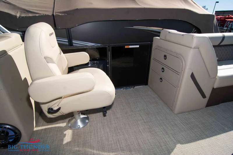 Slide: The Image of 2024 Crest Classic DLX 240 SLC boat interior with beige captain's chair and storage compartments. - 33