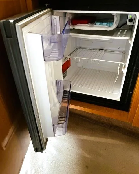 Slide: The Image of Open mini fridge inside 2001 Regal 2960 Commodore Cruiser, showing empty shelves and door compartments. - 15