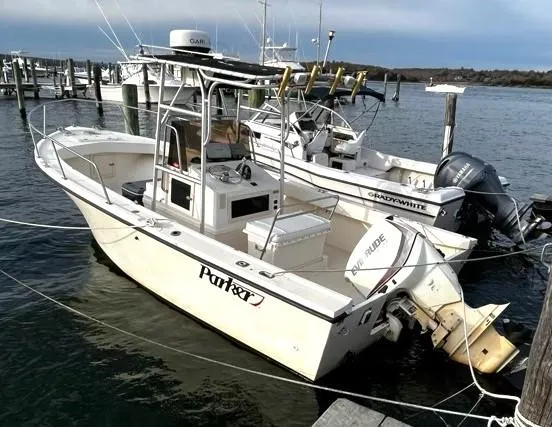 Slide: The Image of 1995 Parker 210 boat docked at marina, featuring open deck and fishing equipment. - 14