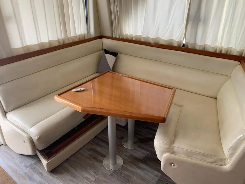 Slide: The Image of Interior seating area of 2000 Riviera 34 Convertible yacht with wooden table and cream cushions. - 15