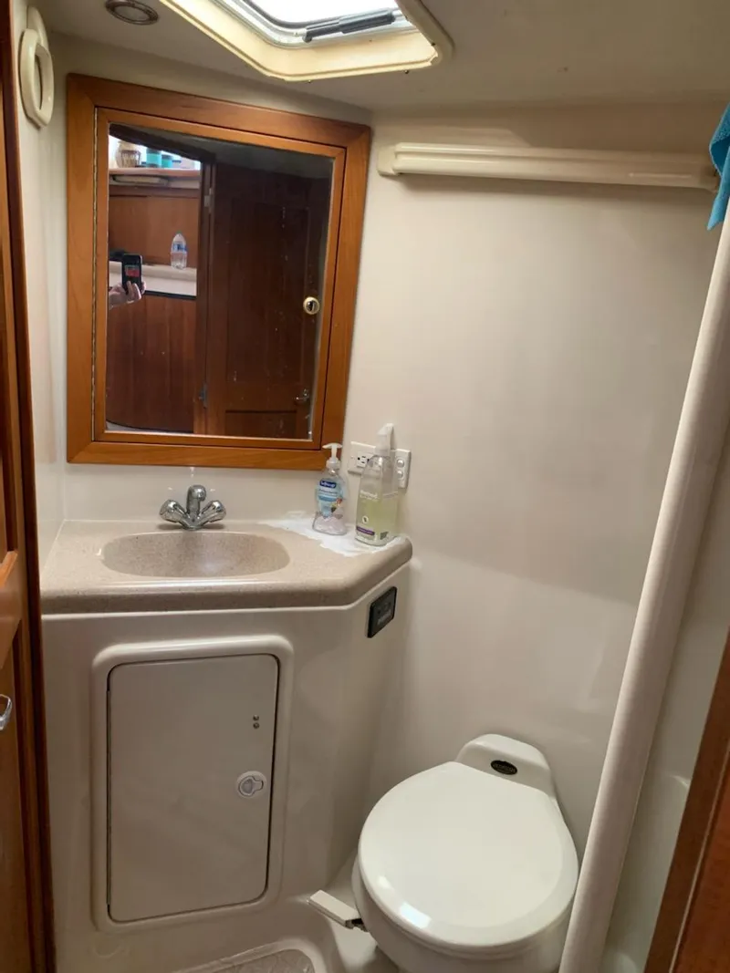 Slide: The Image of Compact bathroom in a 2000 Riviera 34 Convertible yacht with sink, mirror, and toilet. - 23