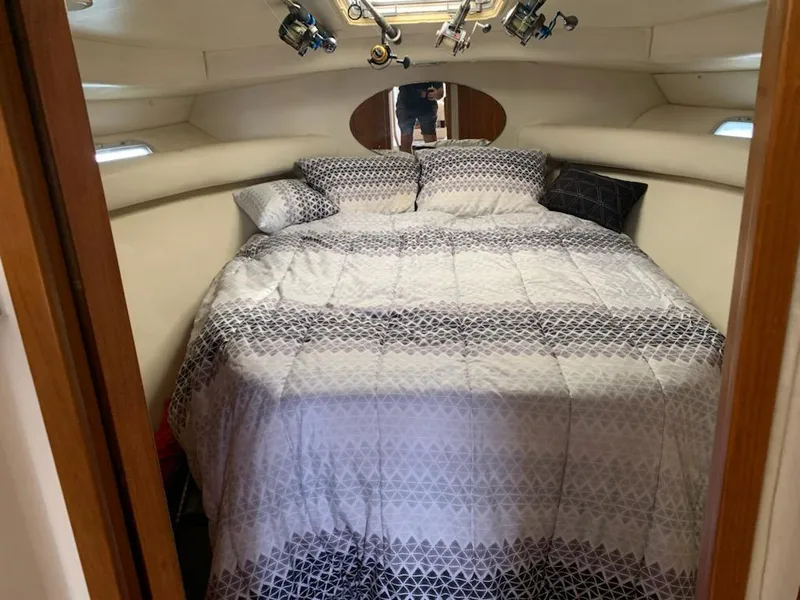 Slide: The Image of Cozy bedroom inside a 2000 Riviera 34 Convertible boat with patterned bedding. - 24