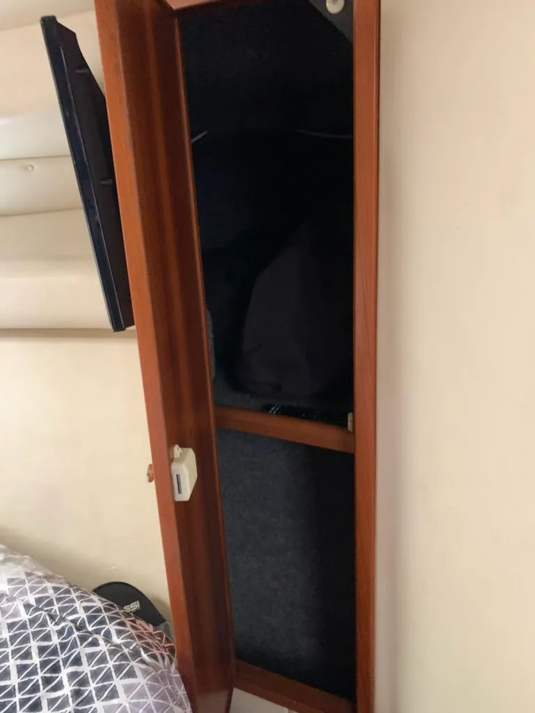 Slide: The Image of Open wooden cabinet inside a 2000 Riviera 34 Convertible boat. - 26