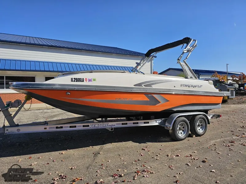 Slide: The Image of 2018 Starcraft Star Step 221 I/O boat on a trailer, orange and white exterior. - 10